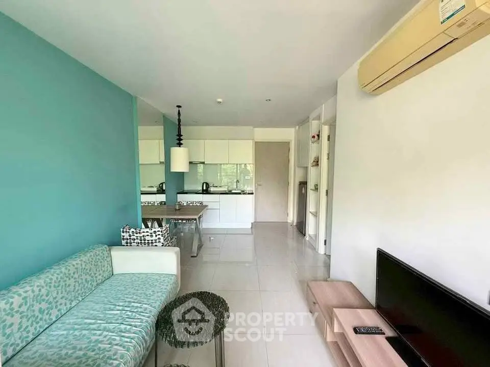 Modern living room with teal accent wall and open kitchen layout