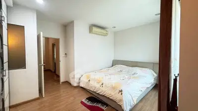 Spacious bedroom with modern decor and natural light, featuring a comfortable bed and wooden flooring.