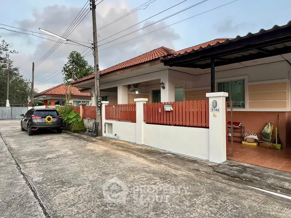 Charming suburban house with red-tiled roof and cozy front porch in a peaceful neighborhood.
