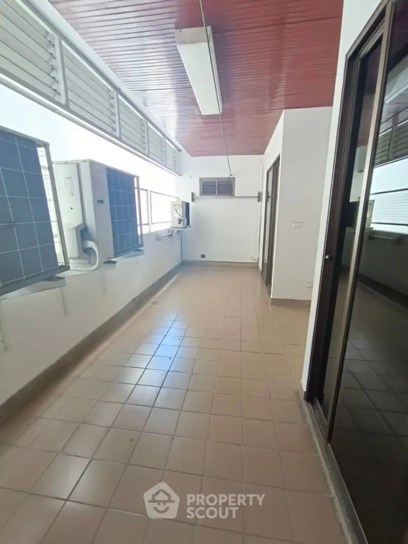 Spacious tiled corridor with air conditioning units and large windows, ideal for ventilation and natural light.