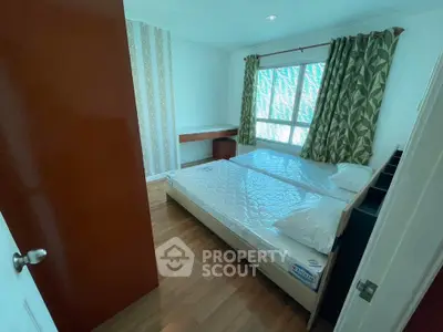 Cozy bedroom with large window and wooden flooring, featuring a comfortable bed and stylish curtains.