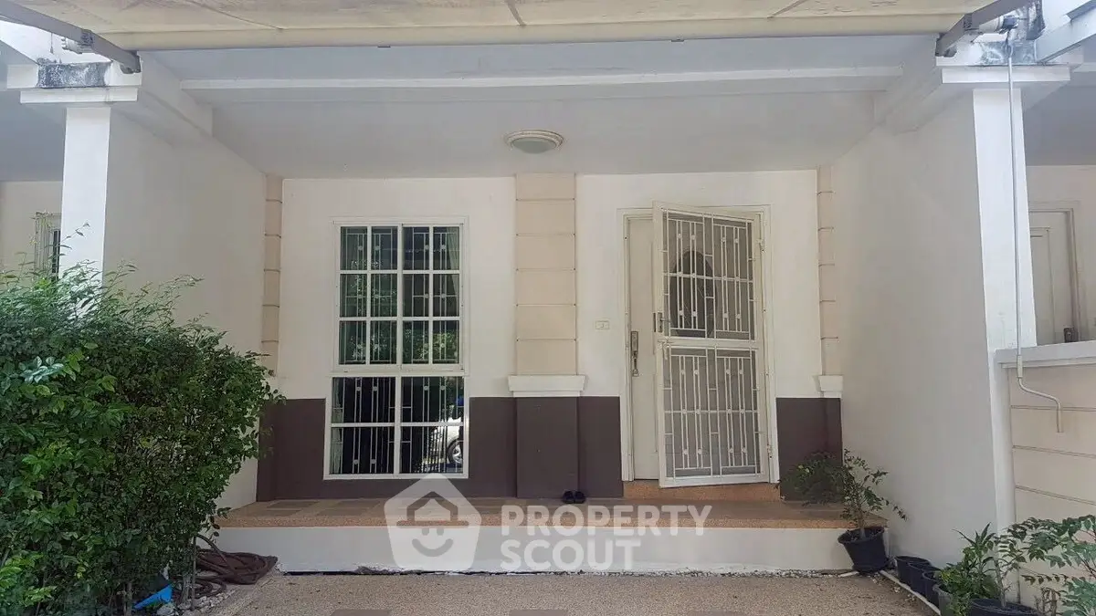 Charming house entrance with secure gated door and lush greenery