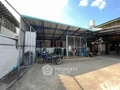 Industrial outdoor storage area with metal roofing and fenced sections