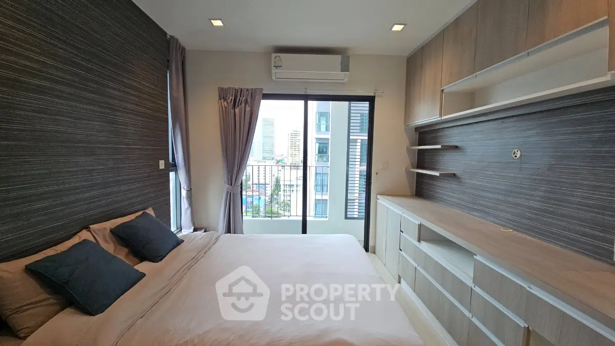 Modern bedroom with city view, featuring built-in storage and sleek design elements.