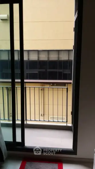 Modern apartment balcony with sliding glass doors and urban view.