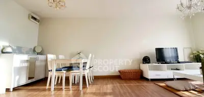 Bright living room with modern furniture and wooden flooring, featuring a dining area and TV setup.