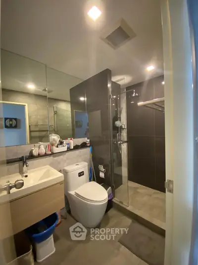 Modern bathroom with sleek design, featuring a glass shower enclosure and contemporary fixtures.