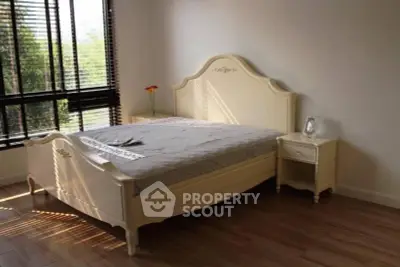 Elegant bedroom with classic bed frame and natural light from large windows.