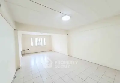 Spacious empty room with tiled flooring and bright lighting, ideal for customization.