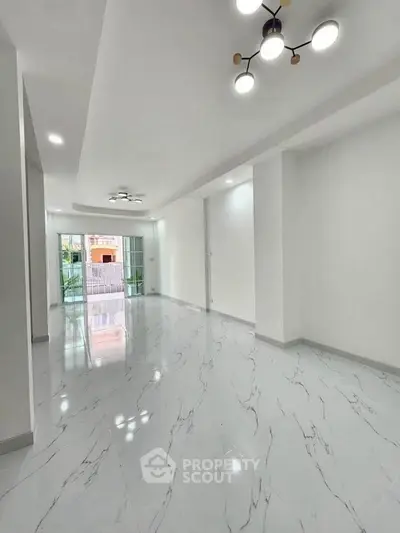 Spacious modern living room with elegant marble flooring and stylish lighting.
