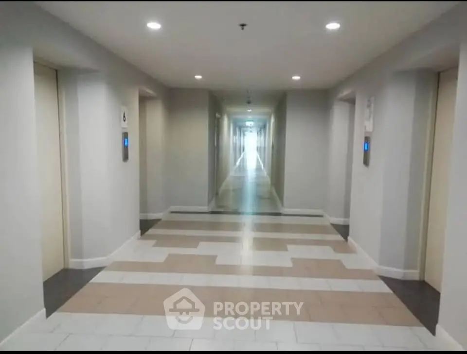 Modern apartment building corridor with multiple elevators and bright lighting.