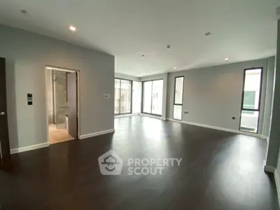 Spacious modern living room with dark wood flooring and large windows