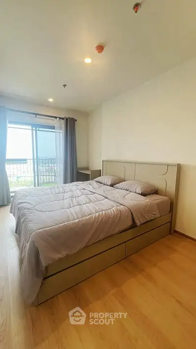 Spacious bedroom with large window and cozy bed, offering natural light and serene ambiance.