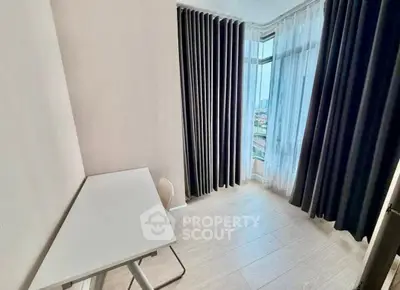 Bright study room with modern desk and large windows offering city views.