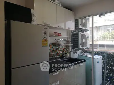 Modern kitchen with stainless steel fridge, washing machine, and colorful backsplash in a compact layout.