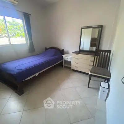 Cozy bedroom with single bed, dresser, and window view in a bright, minimalist setting.