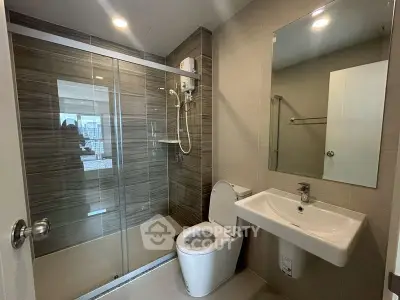 Modern bathroom with glass shower enclosure and sleek fixtures in a contemporary apartment.