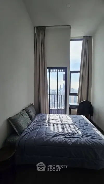 Modern bedroom with tall windows and city view, featuring a cozy bed and elegant curtains.