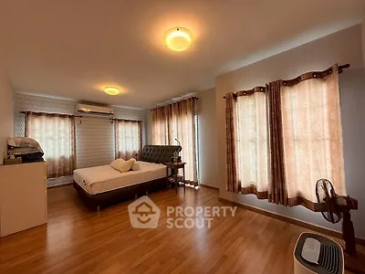 Spacious bedroom with wooden flooring and elegant curtains