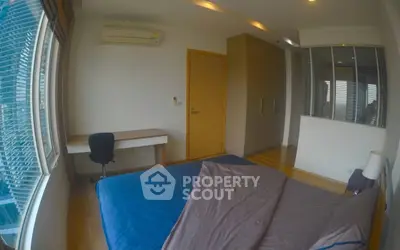 Modern bedroom with large window and wooden flooring, featuring a desk and air conditioning.