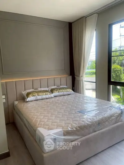 Luxurious bedroom with elegant decor and large window offering natural light.