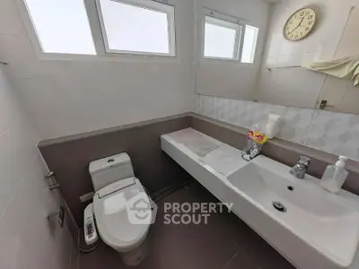 Modern bathroom with sleek fixtures and large mirror, featuring a contemporary design.