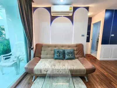 Stylish living room with modern sofa and glass coffee table, featuring elegant lighting and wooden flooring.