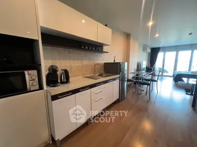 Modern open-layout kitchen with sleek appliances and dining area in a bright apartment.