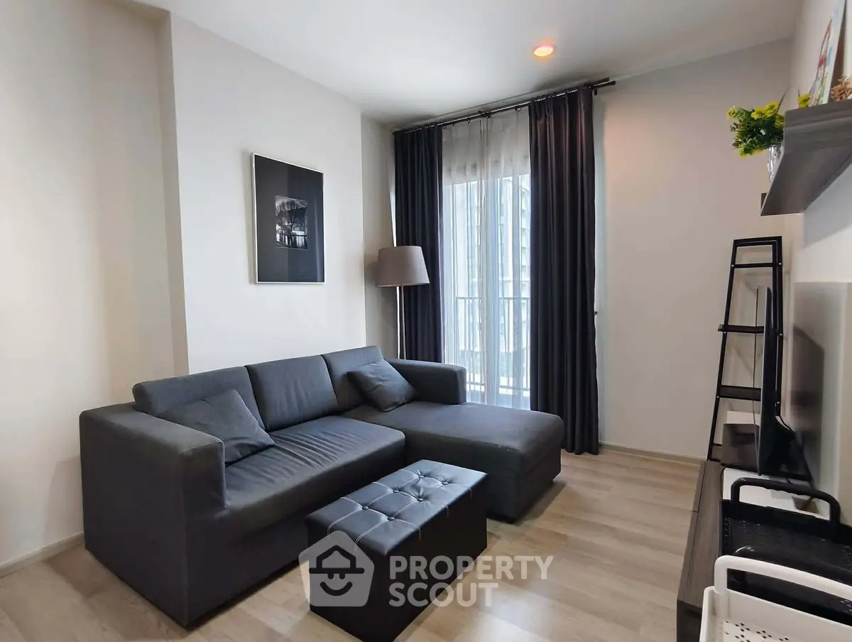 Modern living room with sleek gray sofa, stylish decor, and large window offering natural light.