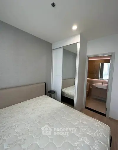 Modern bedroom with mirrored closet and ensuite bathroom in stylish apartment.