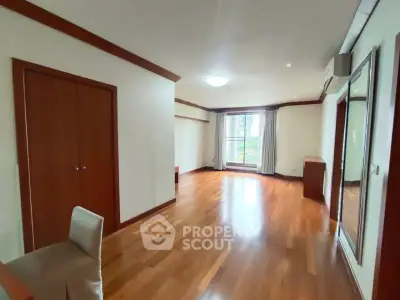 Spacious living room with wooden flooring and large windows in modern apartment.
