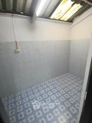 Compact tiled storage room with overhead lighting and patterned floor tiles.