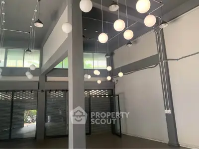Spacious commercial space with modern lighting and large windows, ideal for retail or office use.