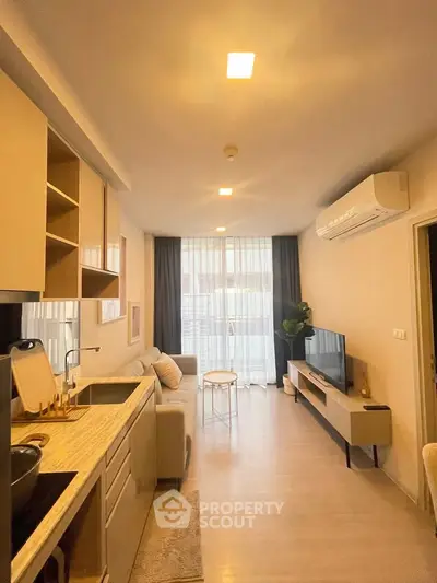 Modern living room with open kitchen, stylish decor, and natural light from large windows.