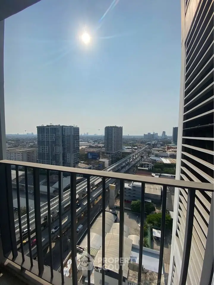 Stunning cityscape view from high-rise balcony with clear skies and urban skyline.