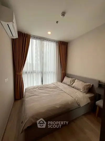 Cozy bedroom with modern decor and large window offering natural light.