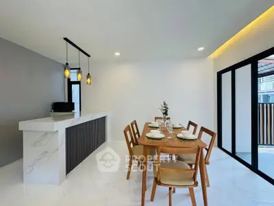 Modern dining area with elegant table and chairs, featuring a stylish open kitchen layout and contemporary lighting.