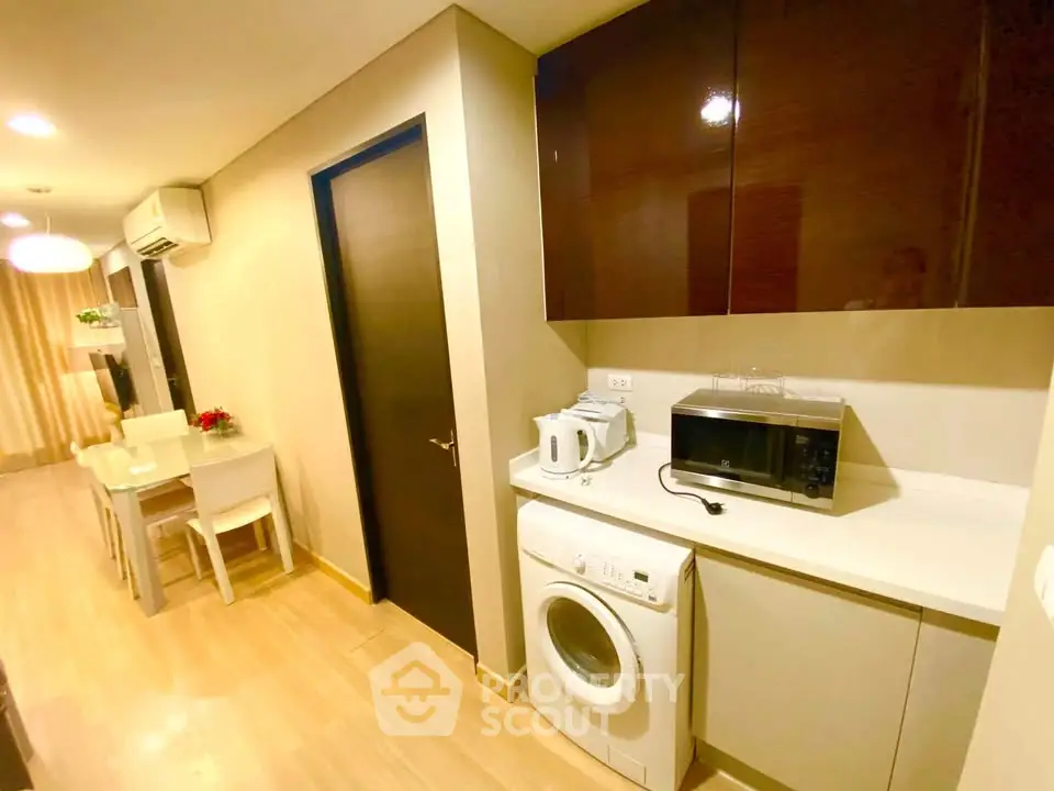 Modern kitchen with washing machine and microwave in cozy apartment