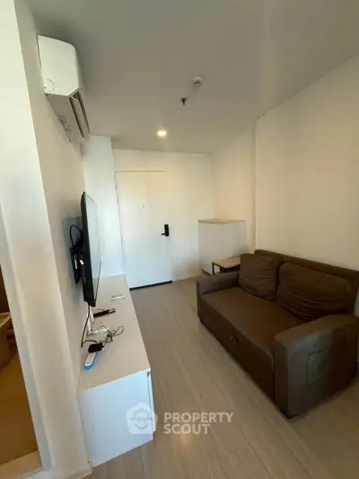 Modern living room with sleek design, featuring a cozy sofa and wall-mounted TV, perfect for relaxation.