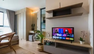 Modern studio apartment with stylish decor and smart TV, featuring natural light and cozy ambiance.