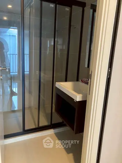 Modern bathroom with glass shower and sleek vanity in contemporary apartment.