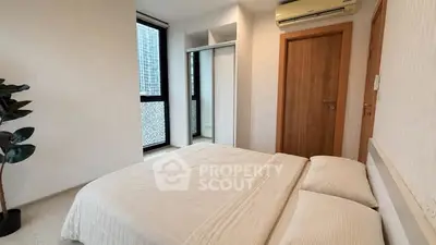 Modern bedroom with large window and mirrored closet in urban apartment
