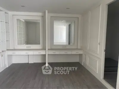 Spacious room with elegant built-in shelves and mirrors, perfect for a stylish home office or study area.