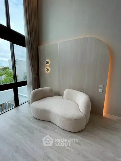 Modern living room with unique sofa and large windows offering natural light