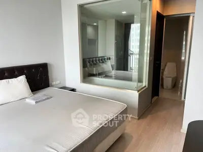 Modern bedroom with glass partition and ensuite bathroom in a stylish apartment.
