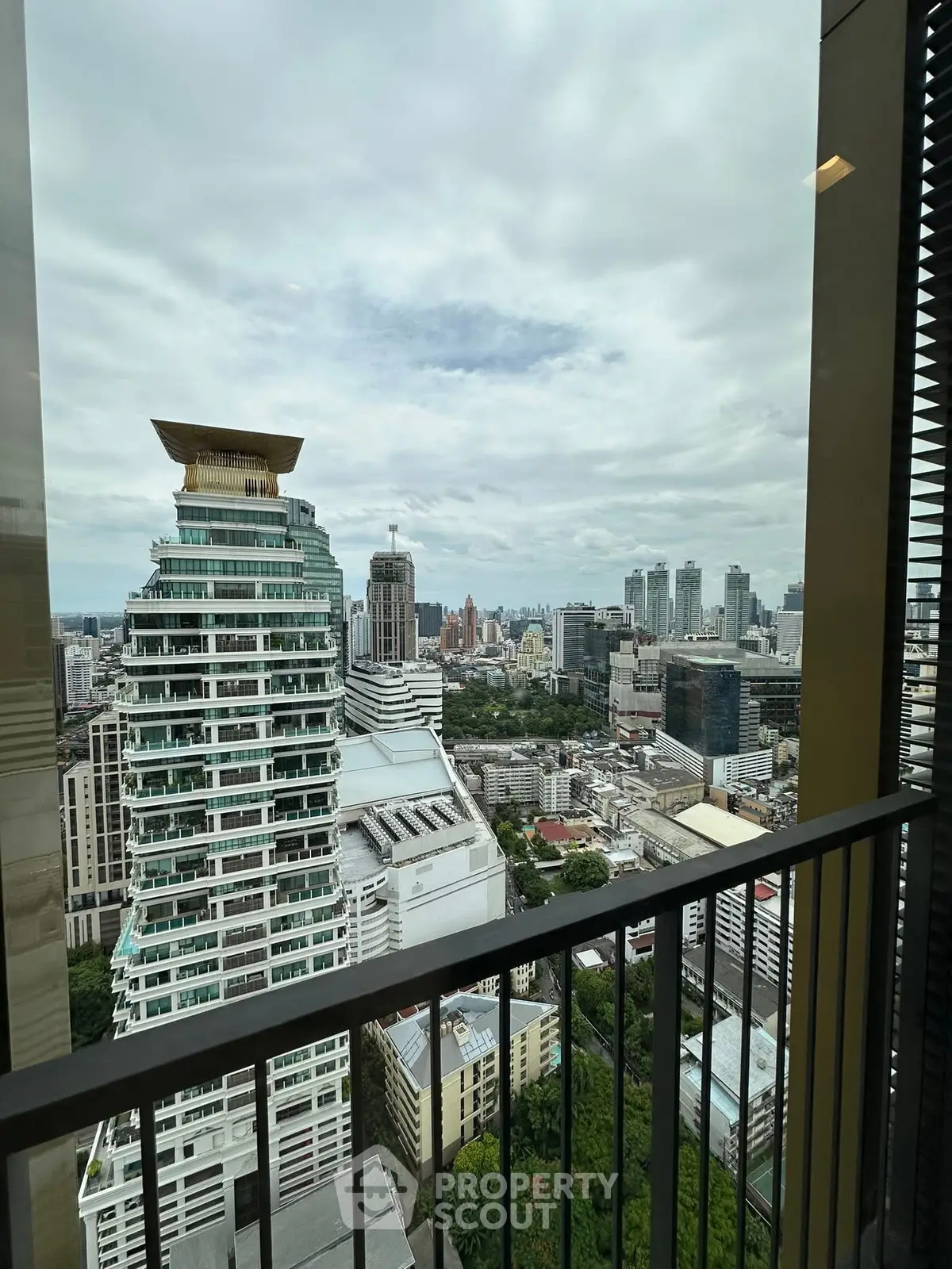 Stunning cityscape view from high-rise balcony with modern architecture and lush greenery.