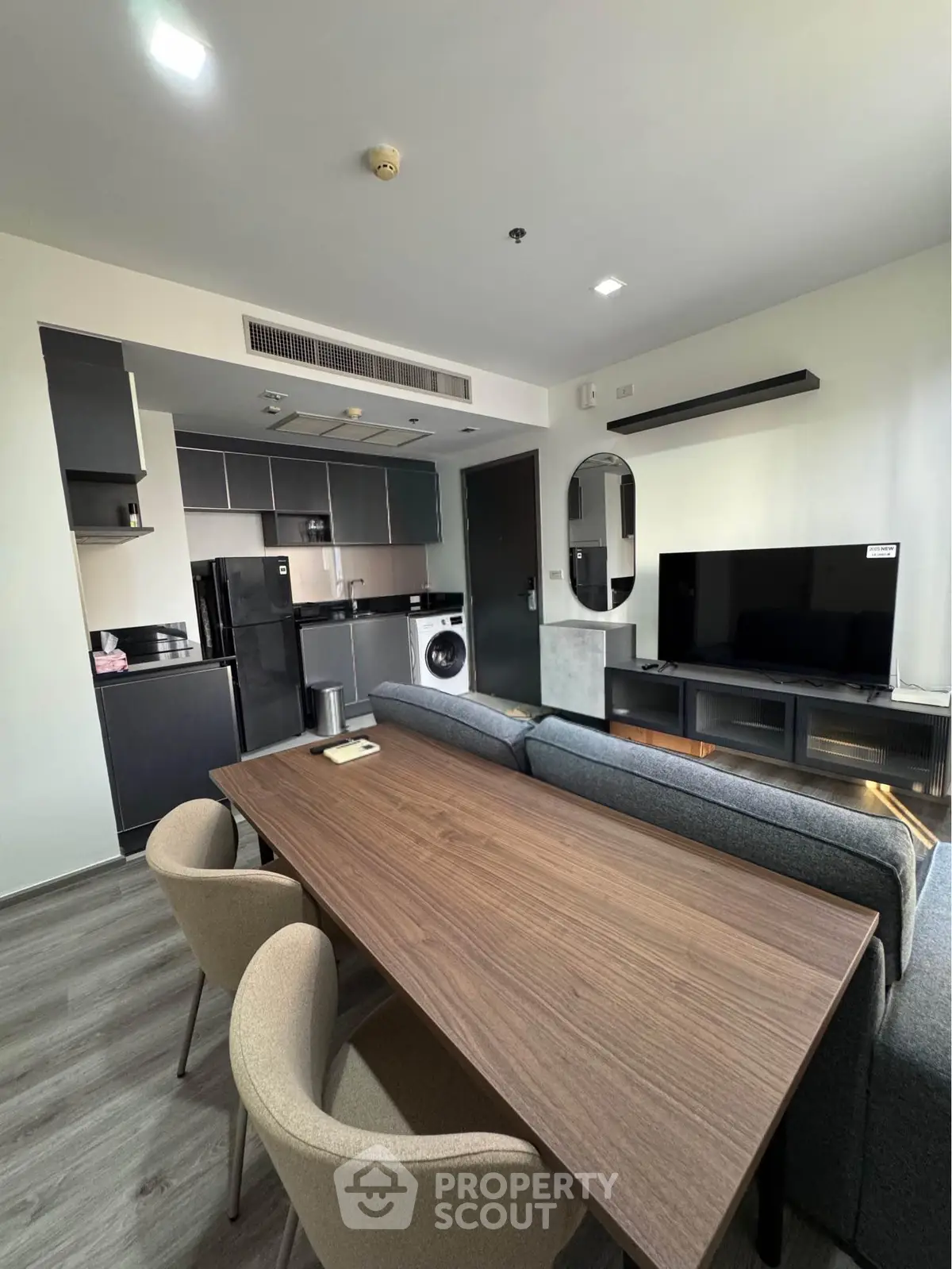 Modern open-plan living room with sleek kitchen, dining area, and stylish furniture in a contemporary apartment.