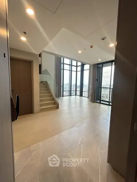 Spacious modern living room with floor-to-ceiling windows and city view.