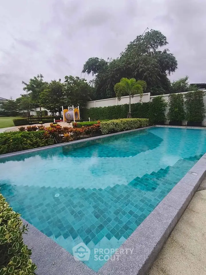 Luxurious outdoor swimming pool with lush greenery and serene ambiance, perfect for relaxation and leisure.