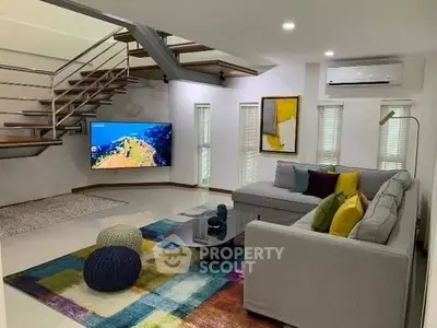 Modern living room with stylish staircase, colorful rug, and cozy sectional sofa.
